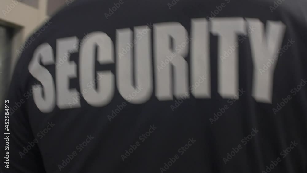 Rear view of a security guard in uniform patrolling in a commercial area.