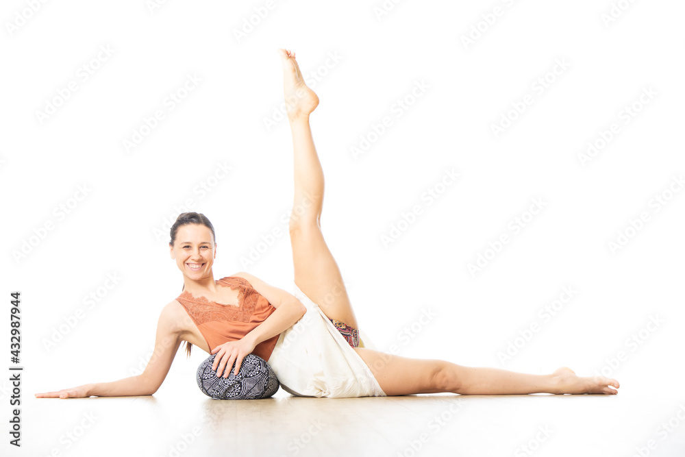 Obraz premium Young sporty healthy woman in bright white yoga studio, lying on bolster cushion, stretching, smilling, showing love and passion for bolster yoga.