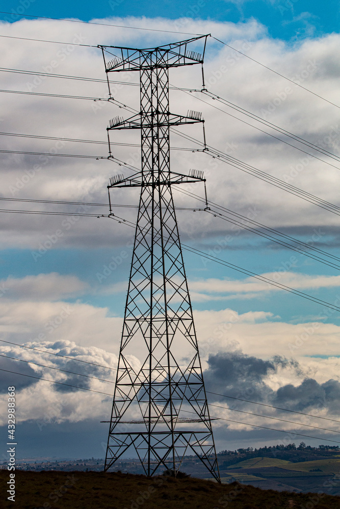 Tall Electricity Pylon Against Blue Cloudy Sky Tall Electricity Pylon Against Blue Cloudy Sky