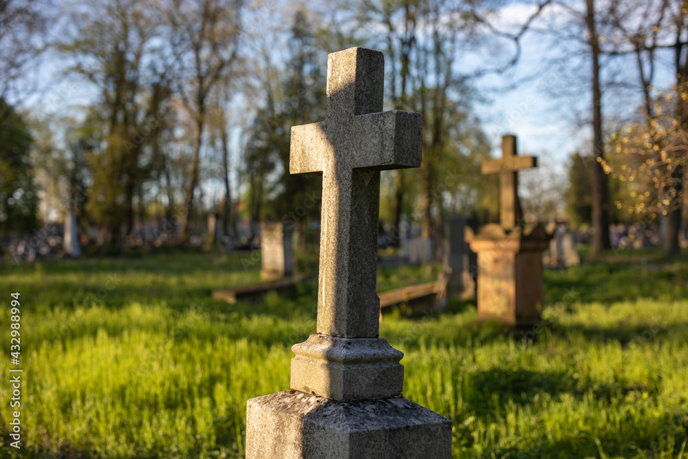 beautiful christian stone cross in an old forgotten cemetery, crosses, resting place, golden light of the setting sun shining upon a gravestone crosses, graveyard in spring