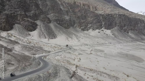 Aerial drone footage of cars and truck traveling in the road of Ladakh. Curvy Road in between the mountains