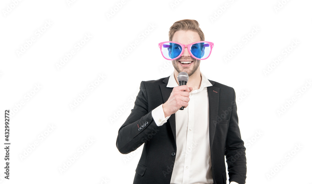 Funny man in business formalwear and party glasses hold microphone happy smiling, showman