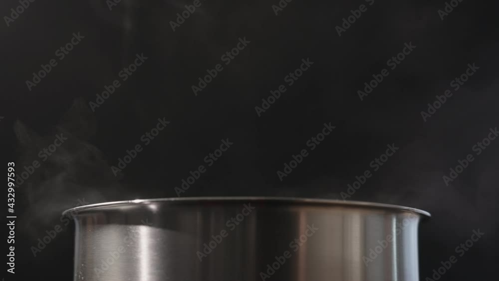Slow motion blow rising steam from pot over black background Slow motion blow rising steam from pot over black background