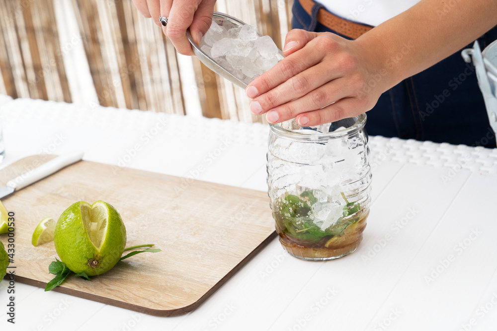 Bartender putting ice cube into shaker while making fresh cocktail with lime juice - obrazy, fototapety, plakaty 
