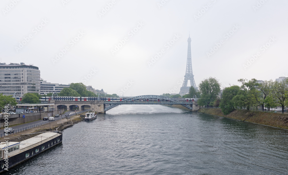 Fototapeta premium View of the Grenelle Bridge. On the embankment are moving cars and pedestrians, along the river-ship