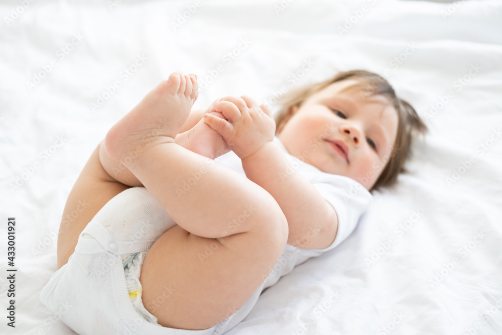 healthy 6 month baby boy smiling and lying on a white bedding at home. selective focus on legs. healthy 6 month baby boy smiling and lying on a white bedding at home. selective focus on legs.