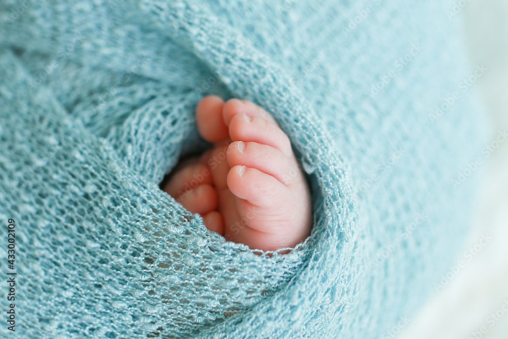 Two cute tiny baby feet wrapped in a blue-green aqua knitted blanket Two cute tiny baby feet wrapped in a blue-green aqua knitted blanket