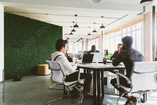 Group of young business people working and communicating while sitting at the office desk together with colleagues sitting. business meeting