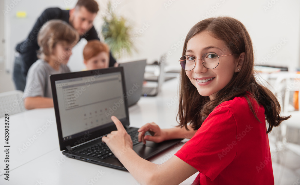 Smiling girl browsing laptop during programming lesson Smiling girl browsing laptop during programming lesson