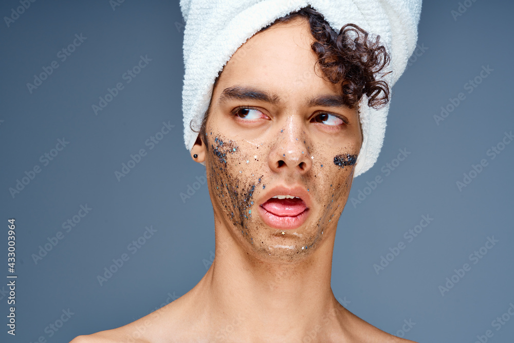 Cheerful guy with bare shoulders with a towel on his head, a black mask on his face Cheerful guy with bare shoulders with a towel on his head, a black mask on his face