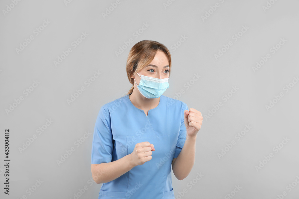 Doctor with protective mask in fighting pose on light grey background. Strong immunity concept