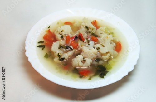plate of rich vegetable soup with cauliflower, carrots, celery and herbs. A bright and delicious dish of vegetarian cuisine. seasoned with parsley