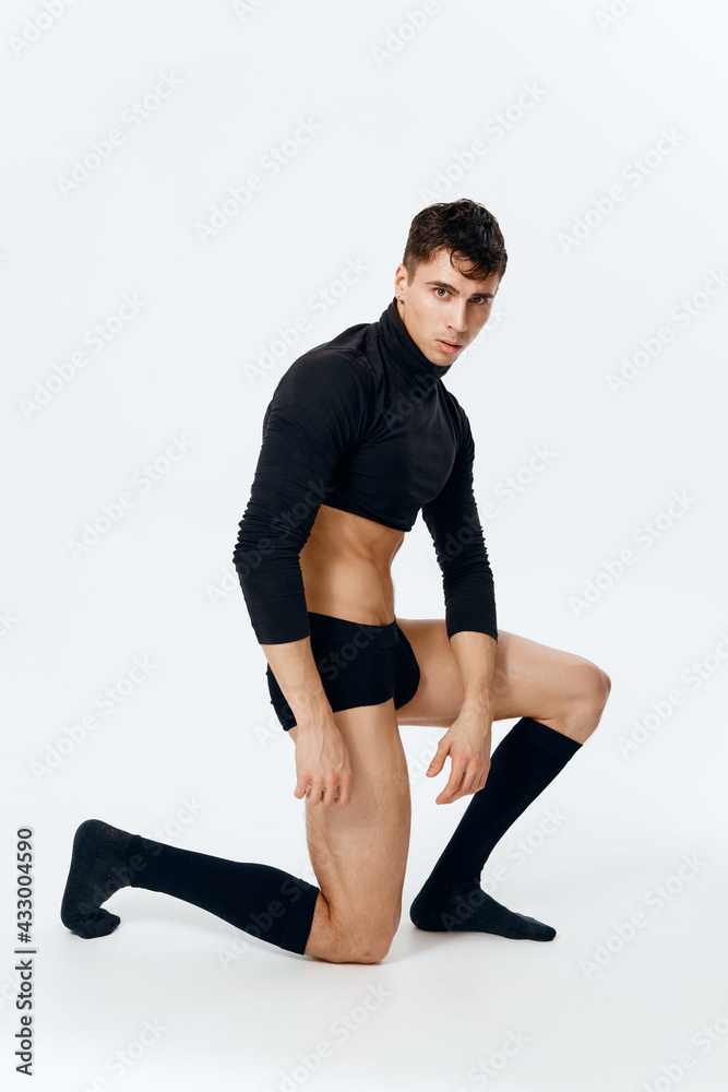 sexy man with an athletic physique kneels in a sweater panties and socks on a light background sexy man with an athletic physique kneels in a sweater panties and socks on a light background