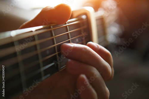 Photography A man's hand on the fretboard of a guitar runs his fingers through the strings and clamps the chords