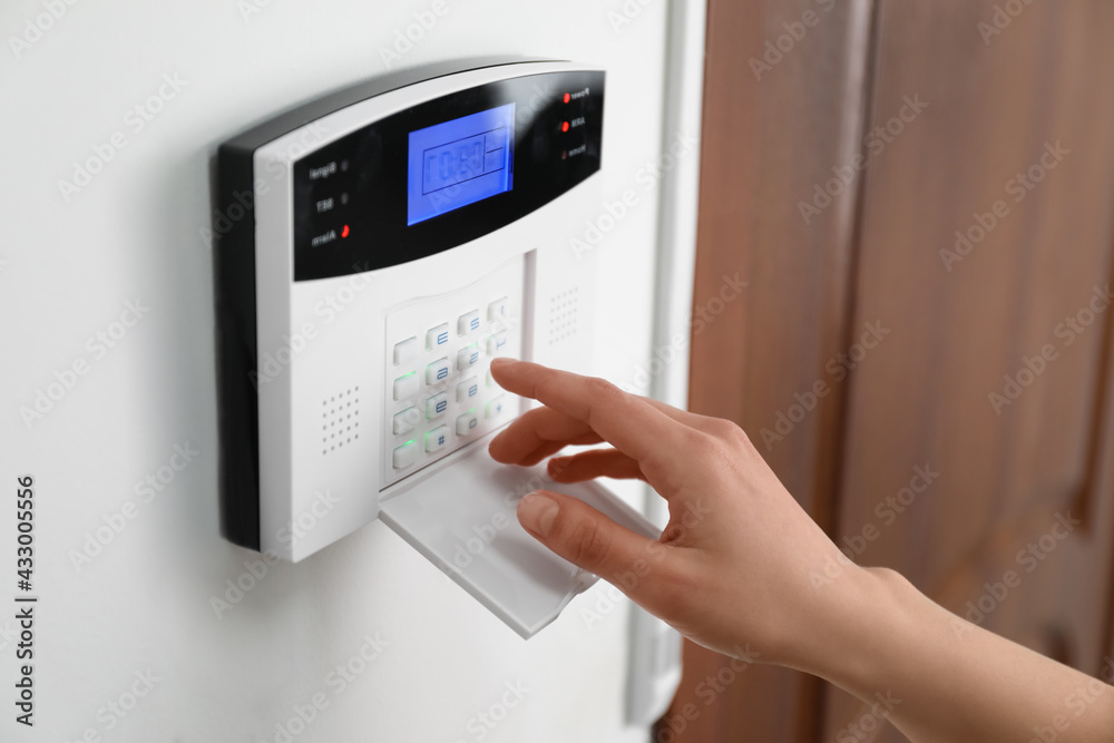Woman entering code on home security system near door, closeup Woman entering code on home security system near door, closeup
