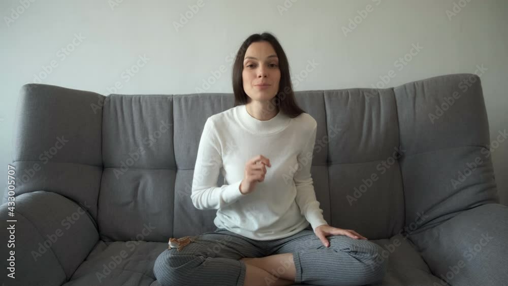 Young smiling woman blogger is talking looking at camera recording blog vlog at home. Freelance work, job, free lifestyle concept. Wearing grey trousers and white blouse. Animal pet bearded agama. Young smiling woman blogger is talking looking at camera recording blog vlog at home. Freelance work, job, free lifestyle concept. Wearing grey trousers and white blouse. Animal pet bearded agama.