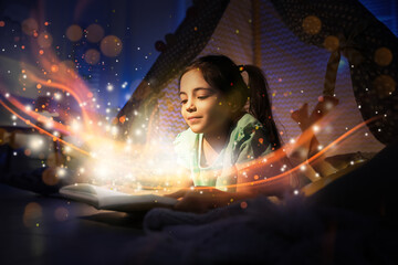Little girl reading fairy tale in play tent at home