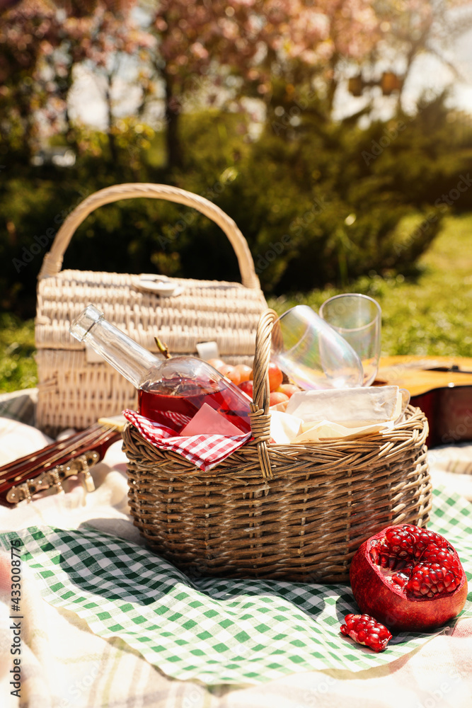 Delicious food and wine in picnic basket on blanket outdoors Delicious food and wine in picnic basket on blanket outdoors