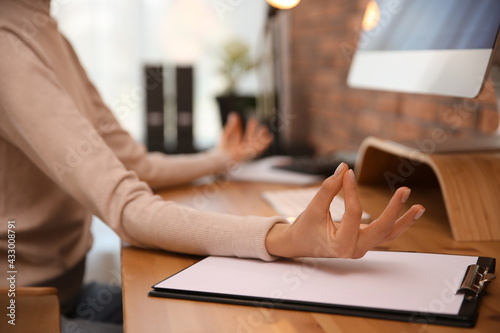 Woman meditating at workplace in office, closeup