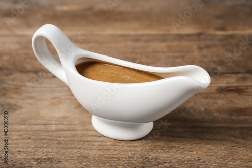 Delicious turkey gravy in sauce boat on wooden table photo