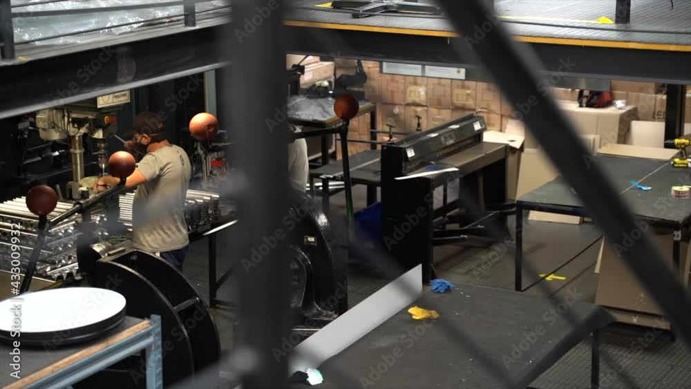 Two men working with metal in a shop with masks on slow motion panning shot Two men working with metal in a shop with masks on slow motion panning shot