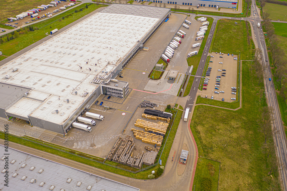 Aerial view of goods warehouse. Logistics delivery  center in industrial city zone from above. Aerial view of trucks loading at logistic center. View from drone.