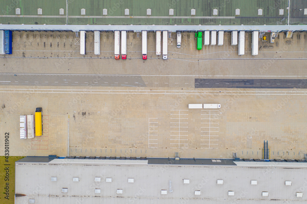 Aerial view of goods warehouse. Logistics delivery  center in industrial city zone from above. Aerial view of trucks loading at logistic center. View from drone.
