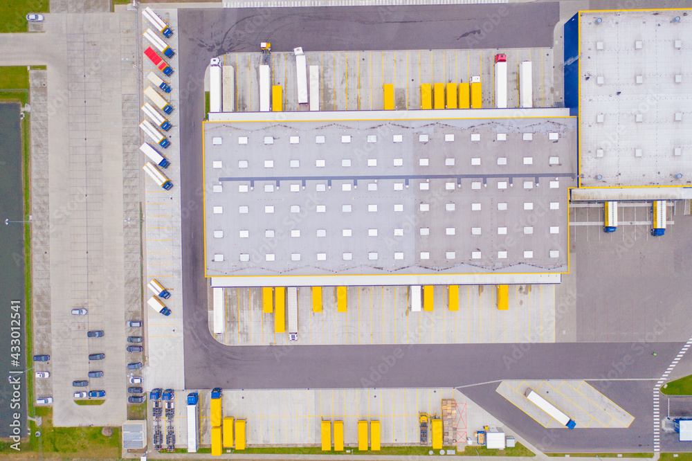 Aerial view of goods warehouse. Logistics center in industrial city zone from above. Aerial view of trucks loading at logistic center. View from drone. Aerial view of goods warehouse. Logistics center in industrial city zone from above. Aerial view of trucks loading at logistic center. View from drone.