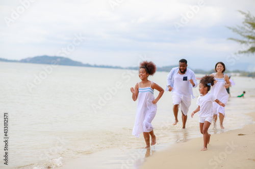 Happy African family walking relax on the beach with 2 daughters.