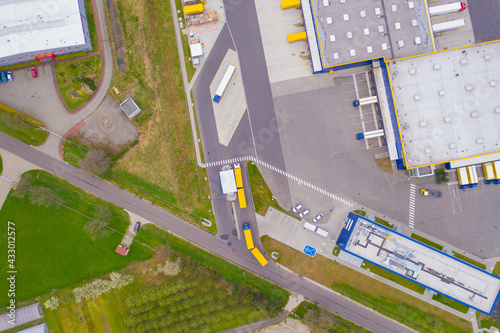 Aerial view of goods warehouse. Logistics center in industrial city zone from above. Aerial view of trucks loading at logistic center. View from drone.