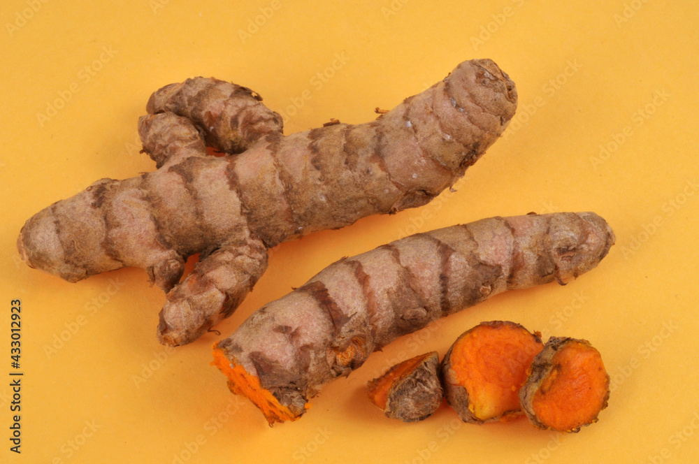 Curcuma frais entier et coupé en gros plan sur fond jaune Curcuma frais entier et coupé en gros plan sur fond jaune