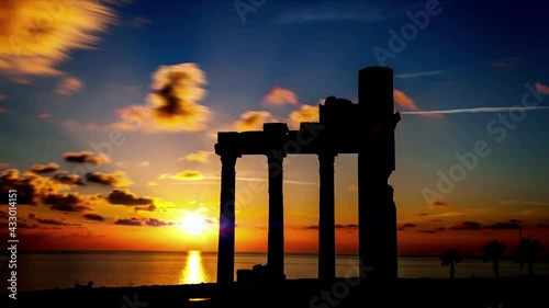Columns of ancient Greek ruins against the backdrop of sunset. Sunset timelapse with orange sky. time lapse
