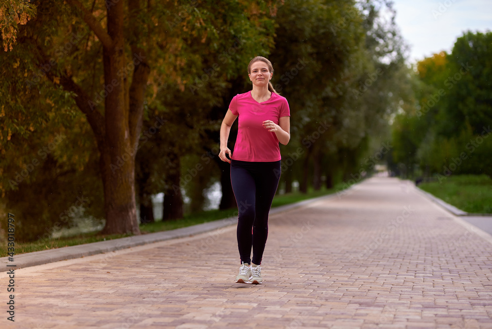 young woman in sportswear walk along  in the park path
