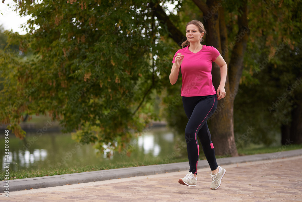 young woman in sportswear runs along in the park path young woman in sportswear runs along in the park path