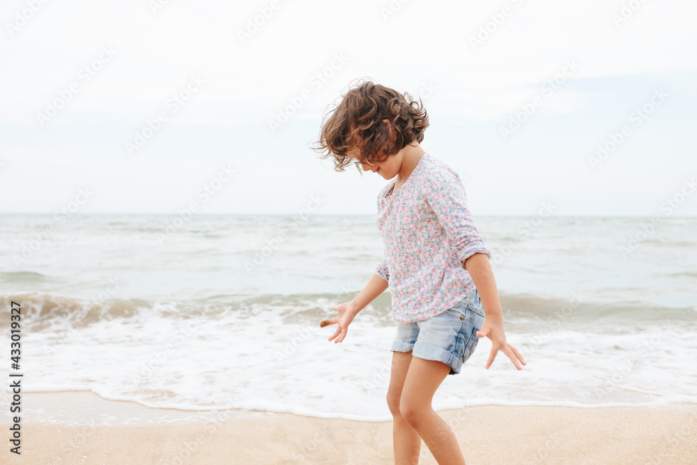 Five years cute curly caucasian girl painting on sand on the beach. Five years cute curly caucasian girl painting on sand on the beach.