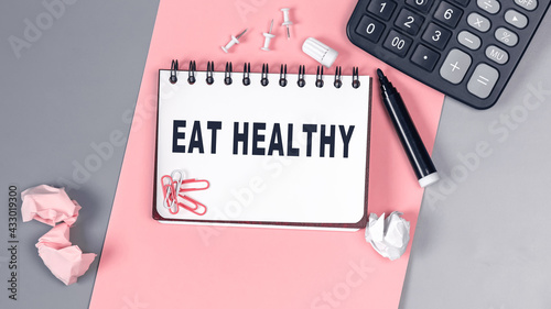 The words Eat Healthy written on a white notebook. Closeup of a personal agenda. Top view. Office concept