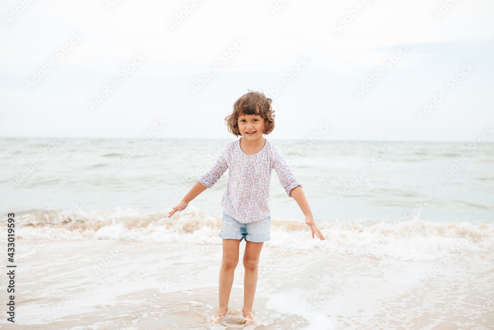 Five years cute curly caucasian girl painting on sand on the beach. Five years cute curly caucasian girl painting on sand on the beach.