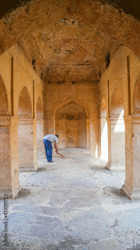 Vertical shot of a male cleaning the stone ground of Neemrana Fort-Palace in Rajasthan, India photo