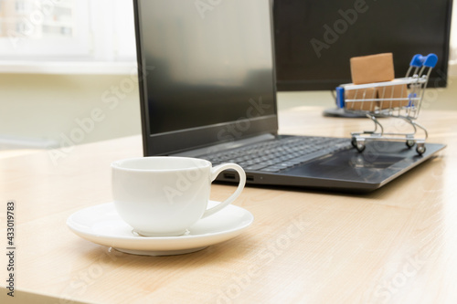 metal chrome cart with boxes on the background of a black laptop and a coffee cup on a working wooden table. selective focus