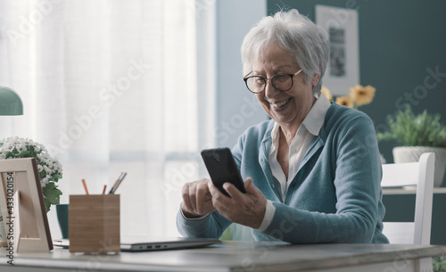 Smiling senior lady using her smartphone photo