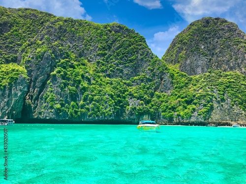 Grüne Vulkaninsel in Thailand mit türkis klarem Wasser umgeben und Booten © Ron