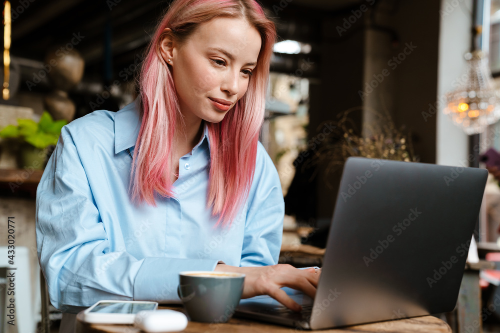 Young white woman with pink hair working with laptop in cafe Young white woman with pink hair working with laptop in cafe
