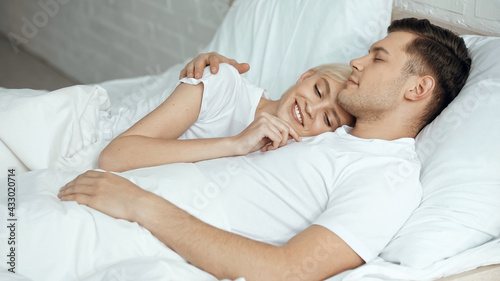 happy blonde woman resting in bed with boyfriend