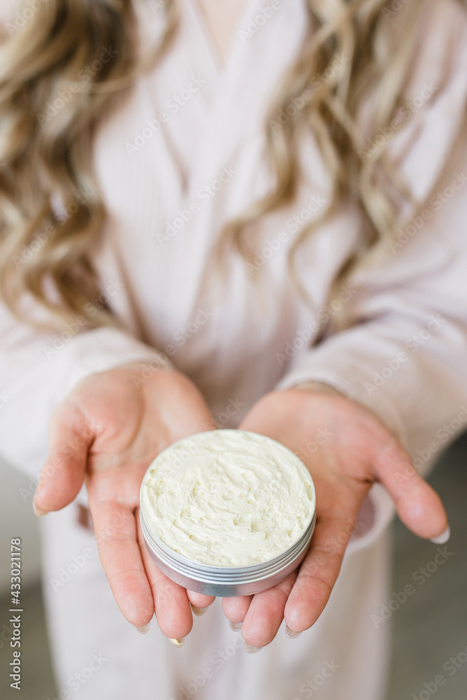 Fototapeta premium a girl with long hair and in a dressing gown holds a cream in her hands