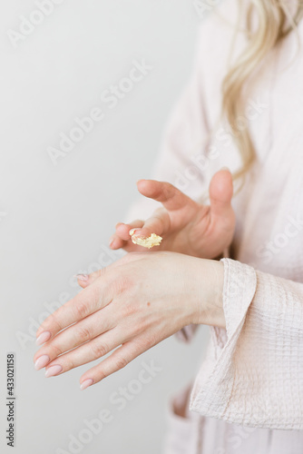 beautiful female hands smear cream close-up on a white background
