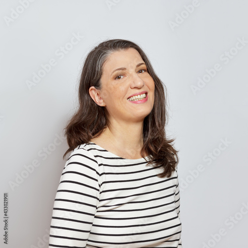 Cover picture portrait of a laughing middle aged woman with beautiful long brown hair, neutral background. © agenturfotografin