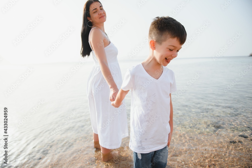 Mother and son playing on the beach at the day time. Concept of friendly family. Mother and son playing on the beach at the day time. Concept of friendly family.