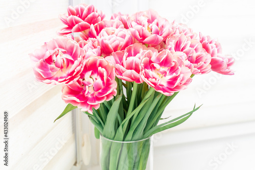 Bouquet of pink and yellow tulips on windowsill white light background. Spring mood and springtime concept.