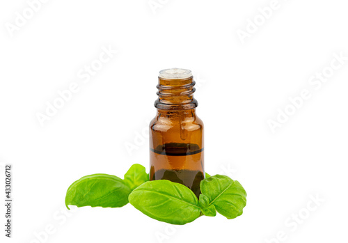 Basil Ocimum basilicum essential oil bottle with green basil leaf next to it, isolated on white background, lot of copy space, studio shot.