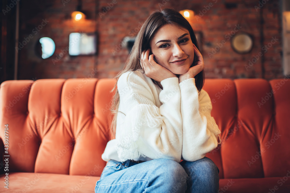 Obraz premium Positive woman on sofa leaning on hands